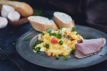 Scrambled eggs with tomatoes on dark background