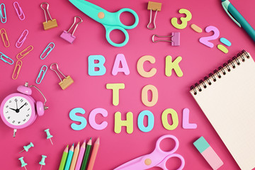 The inscription in colored letters, Back to the School. Stationery and school supplies in disorder on a red background.