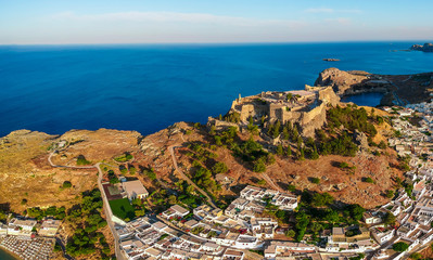 Aerial birds eye view drone photo of village Lindos, Rhodes island, Dodecanese, Greece. Sunset panorama with castle, Mediterranean coast and Saint Paul bay. Famous tourist destination in South Europe