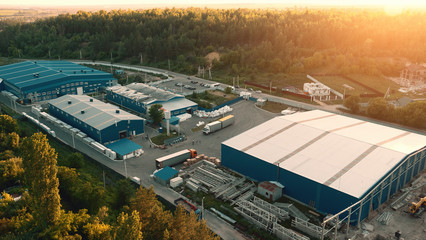 Aerial view of warehouse storages or industrial factory or logistics center from above. Aerial view of industrial buildings at sunset - obrazy, fototapety, plakaty