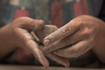 Fototapeta na wymiar Female potter works with clay, craftsman hands close up with selective focus