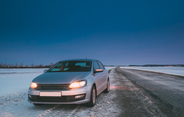 Naklejka premium Car Sedan In Country Road At Winter Evening