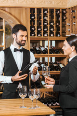 couple of wine stewards pouring wine into glass for degustation at wine store