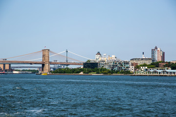 Fototapeta na wymiar New York City / USA - JUL 14 2018: Brooklyn Bridge view from Governors Island ferry on a clear afternoon