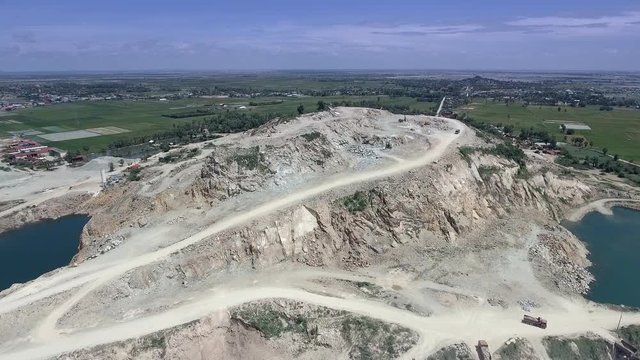 aerial drone shot : fly over a mountain stone quarry with dump trucks loaded with stone