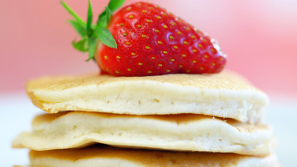 Stack of pancakes with strawberry on top, macro closeup.
