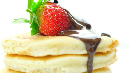 Stack of pancakes with strawberry and drizzled with chocolate sauce, macro closeup.