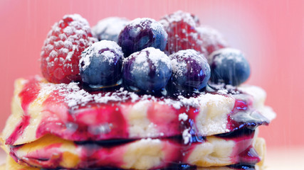 Stack of pancakes with raspberries, blueberries and drizzled with blueberry maple syrup, macro closeup.