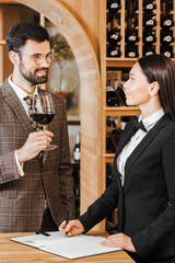 wine steward making notes while talking to client at wine store