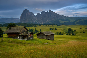Fototapeta na wymiar Sassolungo mountains on the Italian Alps Dolomites with wood houses on the foreground