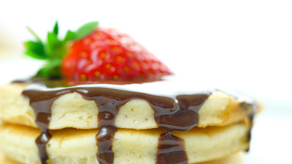 Stack of pancakes with strawberry and drizzled with chocolate sauce, macro closeup.