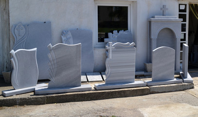 A small private firm produces gravestones and exposes samples of its products along the sidewalk