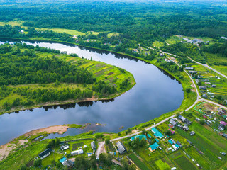 Bird's eye view of the green forests, river and the village. Karelia, Russia.