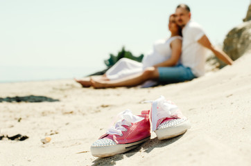 Obraz premium photo shoot of a pregnant couple on the beach. the girl has red hair . small sneakers pink
