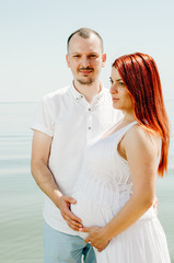 photo shoot of a pregnant couple on the beach. the girl has red hair