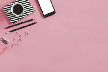 Minimalistic composition of creative desk with mock up phone screen, cup of coffee and office accessories. Pink background with copy space for inscription.