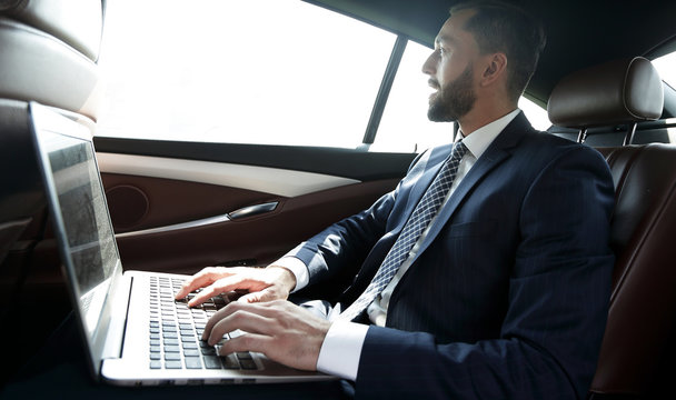 Businessman typing text on laptop while sitting in car