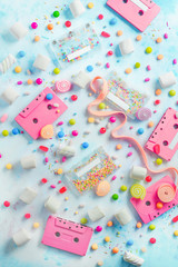 Obraz na płótnie Canvas Pink cassette tapes in a sweet sounds concept. Candies, sprinkles and marmalades on a light background with copy space. Pastel color flat lay