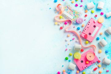 Pink cassette tapes in a sweet sounds concept. Candies, sprinkles and marmalades on a light background with copy space. Pastel color flat lay header