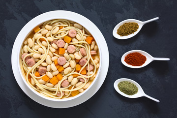 Chilean traditional Porotos con Riendas dish of cooked dried bean, pumpkin, onion, spaghetti, sausage, the spices cumin, paprika, oregano, photographed overhead (Selective Focus on the dish)