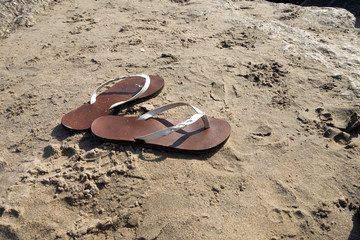 woman's sandals flip flops on the sandy beach