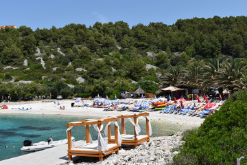 Beach cabanas and motorboat on the Dalmatian coast of the turquoise Adriatic sea in Europe. Fantastic sheltered shingle bay and public beach summer in Croatia Sunbeds and parasols against extra charge