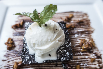 Warm chocolate brownie with ice cream and mint leaves walnuts and caramel