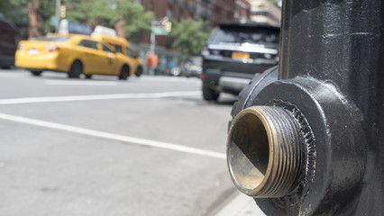 open spigot, close up, fire hydrant, low angle, blurred new york city street in motion, yellow taxi