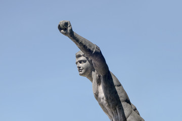 statue sculpture on man with vitory fist raised on blue shy