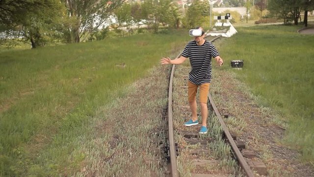 A young man is on the rails for rail transport in a virtual reality helmet.View images, video games.The world of virtual reality