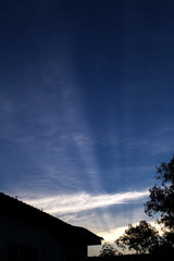 Raios do por do sol cruzando ceu azul