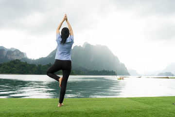 Young girl doing yoga fitness exercise outdoor in beautiful mountains landscape. Morning sunrise,...
