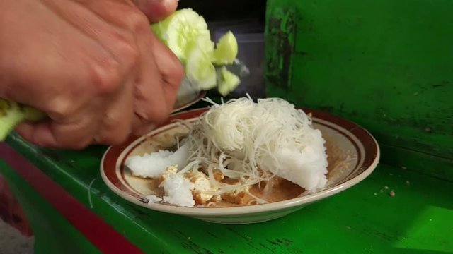 Cutting cucumber on top of traditional indonesian food, ketoprak