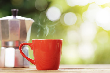 red cup of coffee with nature green background