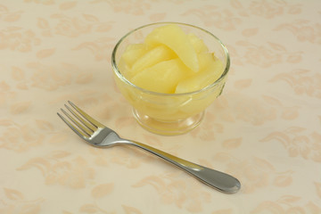 Canned pear slices in glass dessert cup with fork on tablecloth