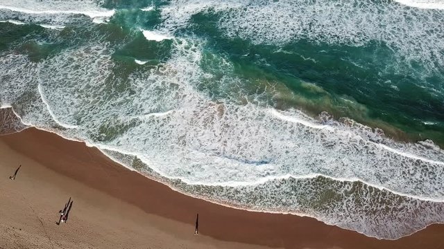 Seascape with waves and shadows of walking people. Top view aerial photo from flying drone of nature landscape turquoise water with Wanda beach in winter day in Cronulla. Travel vacation concept.