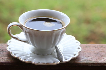 Close up black coffee in white ceramic cup on green background
