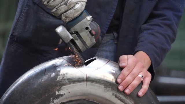 Portable disc grinder polishing a hole on an aluminium tube