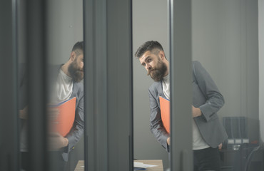 Business man looking out through glass doors in office