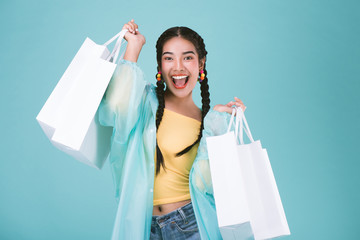 Happy young woman in raincoat with shopping bags,shopping in rainy day sale concept,over blue...