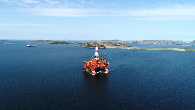 Aerial footage of Oil and Gas Drilling rigs POI shot of a semi submersible and a jackup the background hot stacked in a bay.