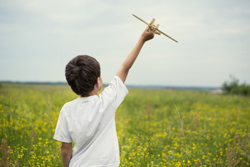 Boy in a field of yellow flowers with the airplane in the hand.