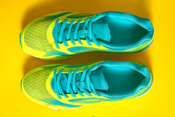 Pair of sport shoes on colorful background. New sneakers on yellow background, copy space. Overhead...