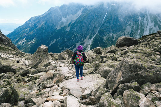 Woman traveler with backpack tracking sticks top mountain - Powered by Adobe