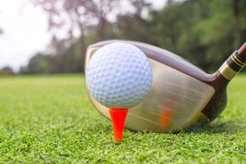 Golf clubs and golf balls on red tee.