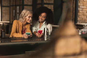 Interesting content. Beautiful young women sitting at the bar counter and looking through social...