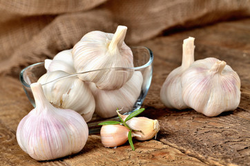 Garlic bulbs and cloves in glass places on rustic wooden boards