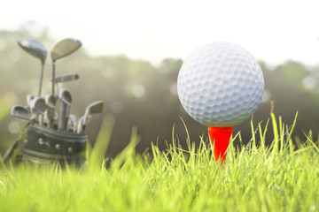 Golf clubs and golf balls on red tee.