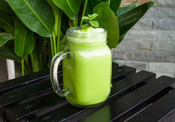 Green tea smoothies in glass on black wooden table.