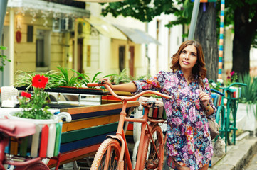 A young woman in a stylish dress on a city street . Girl on a walk around the city